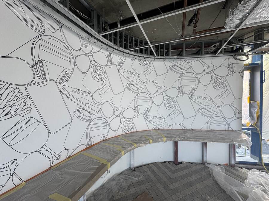 Wall graphic installed on a curved wall ahead of ceiling close-in, bench still under protection.