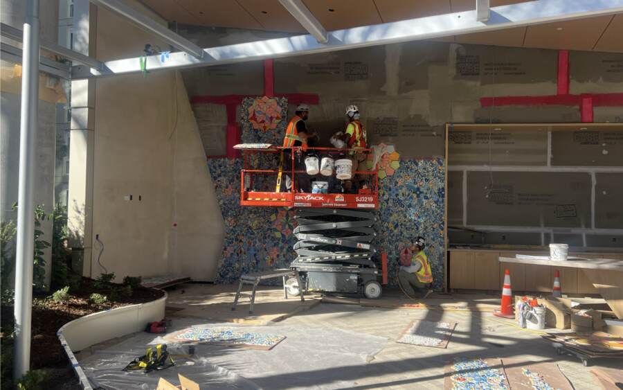 Mosaic install from a scissor lift, with trades working the same room.